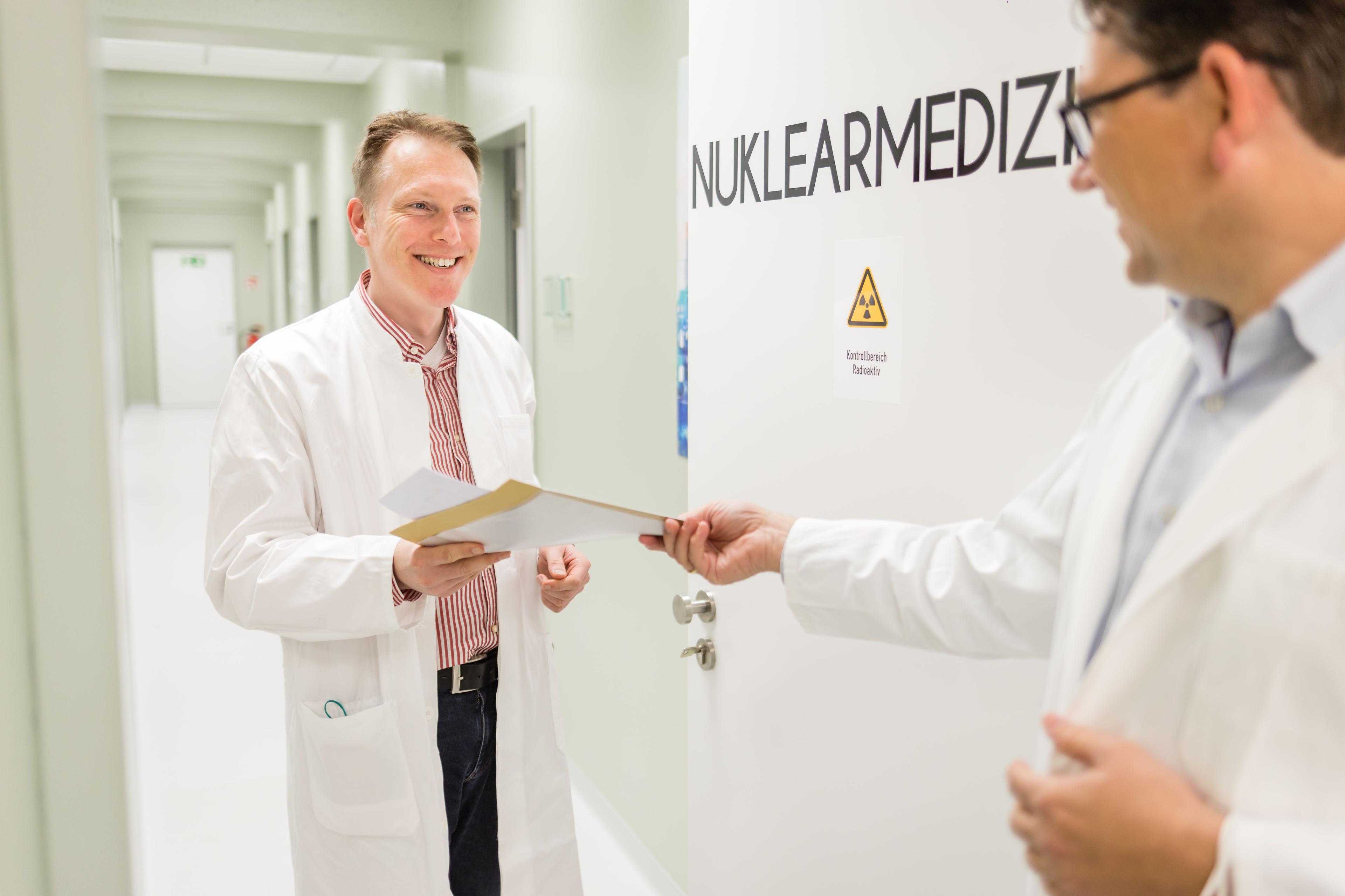 Dr. med. Thorsten Pöppel spricht im Flur mit seinem Kollegen der Nuklearmedizin, Clemens Spohn.